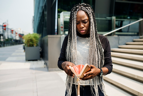 A young black woman looks at her wallet