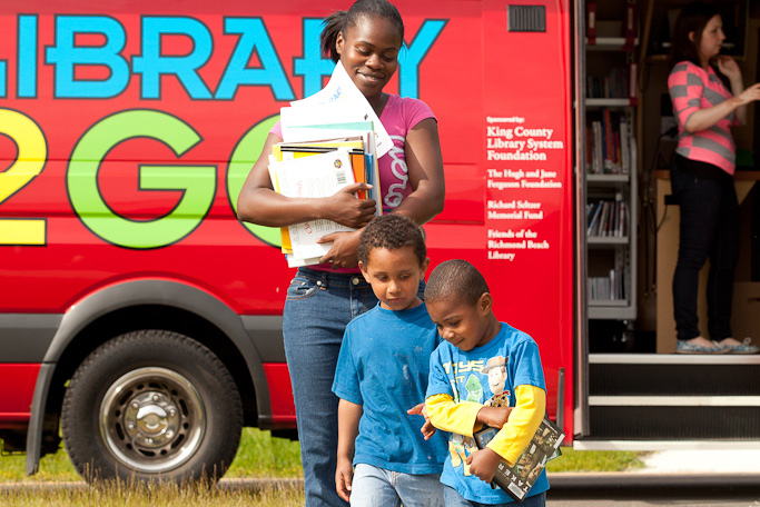 A mom and her sons walk back from a mobile library at YWCA's Passage Point location