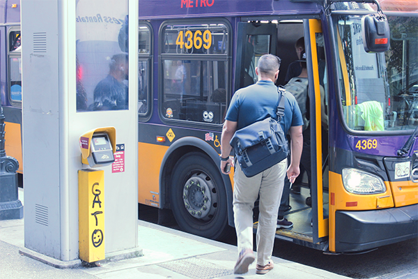 A rider boards a bus next to a Rapid Ride pay station