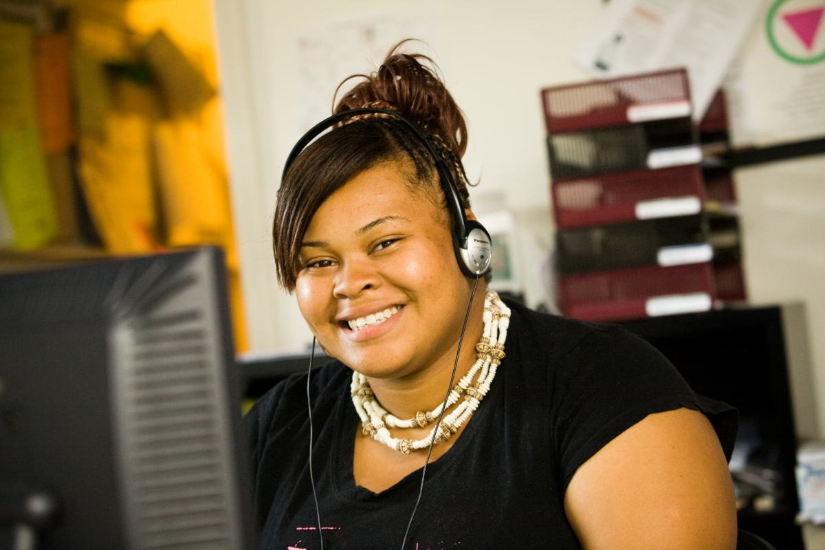 A Black woman smiles while working from home on her computer