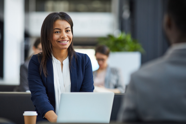 Picture of a Black woman in business casual working on a laptop