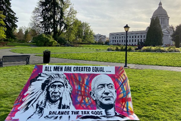 An art piece featuring paintings of Chief Seattle and Jeff Bezos with the words "all men are created equal, balance the tax code" sits in front of the Washington Capitol Building
