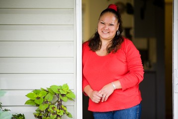 A woman stands in the doorway of her home