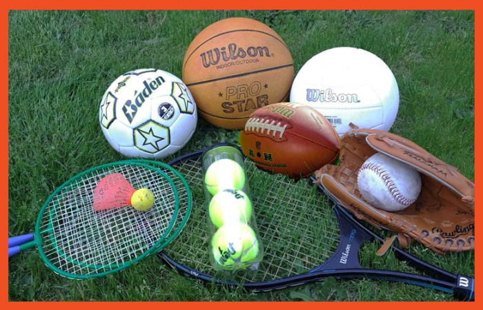 Photo of various sports equipment and balls lying on grass.