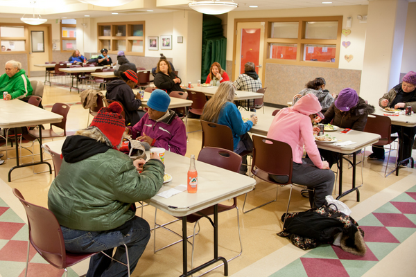 Women sitting down and eating inside Angeline's Day Center.