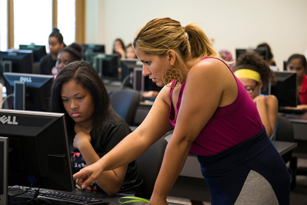 A teacher helps a student use the computer