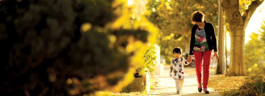 Woman walking with a young girl down a sidewalk.