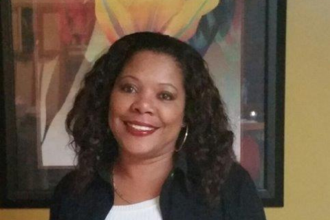 Photo of YWCA Director Doris O'Neal standing in front of a framed piece of art