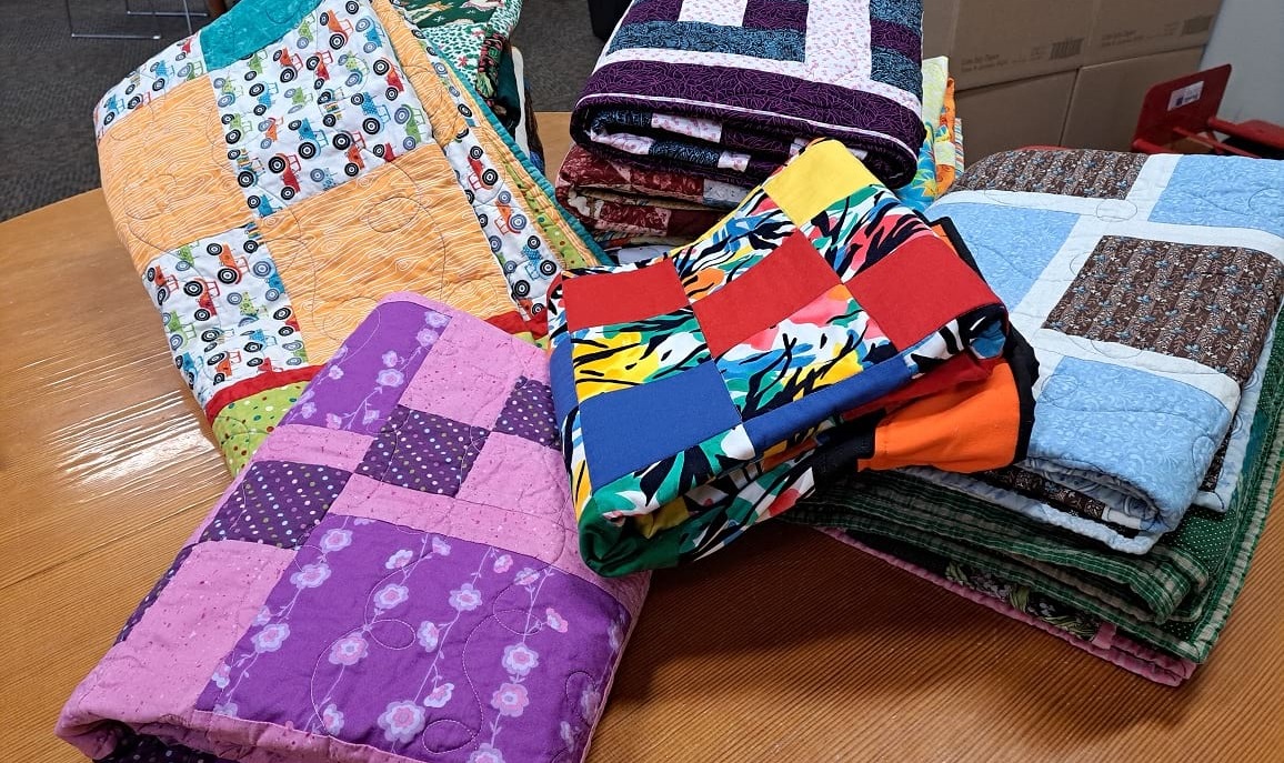A pile of folded quilts lying on a table.
