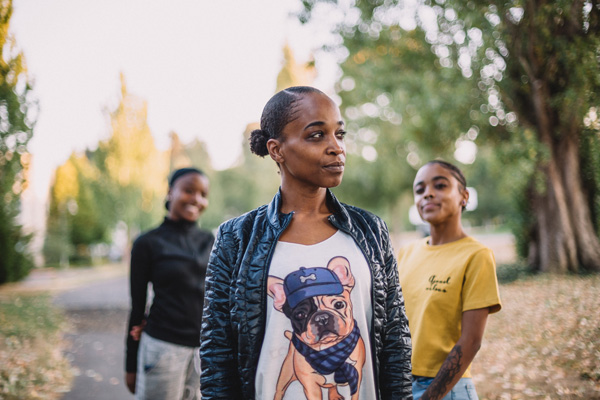 A Black woman stands with her two daughters