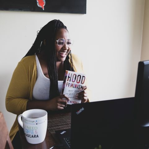 Photo of woman showing a book to her video conference