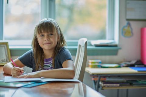 A young girl does her homework at the kitchen table.