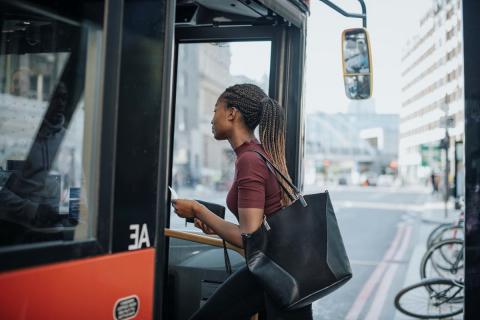 A black woman boards a city bus