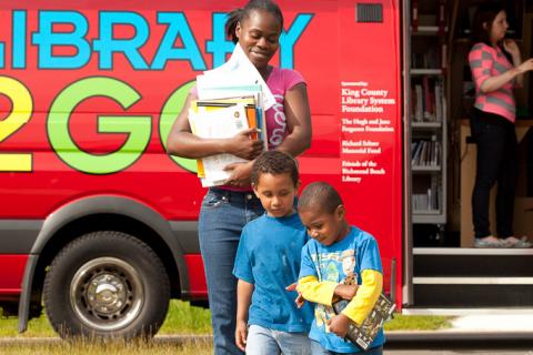 A mom and her sons walk back from a mobile library at YWCA's Passage Point location