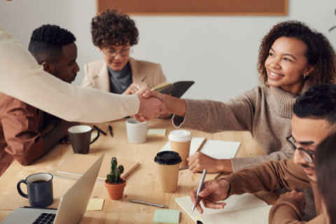 Picture of five people of different races sitting around a work station