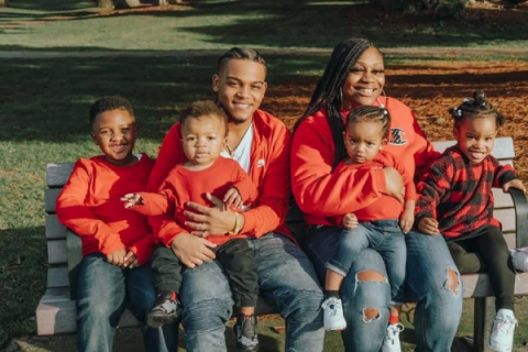 Picture of a six-person family dressed in red and blue on a park bench