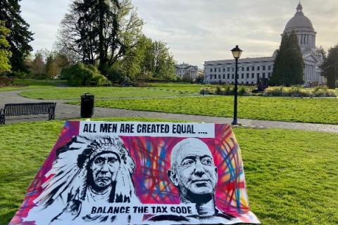 An art piece featuring paintings of Chief Seattle and Jeff Bezos with the words "all men are created equal, balance the tax code" sits in front of the Washington Capitol Building