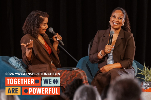 Photo of Angela Poe Russell and Laila Ali together on stage at the 2026 Inspire Luncheon with orange banners behind them that read "Together We Are Powerful"