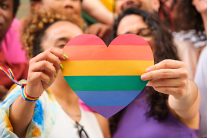 A photo of two people holding up a rainbow heart.